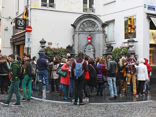 People taking photos of a young boy having a wee...