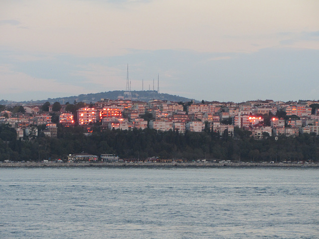 Sailing from Istanbul, windows of the Asian side of the city blaze in the setting sun.