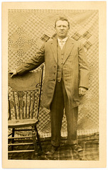 A Man Posing with a Chair, Quilt, and Blanket