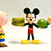 Charlie Brown Looks On in Amazement as Mickey Mouse Poses with Turtle Boy in His Left Hand and a Stack of Pickle Slices in His Right