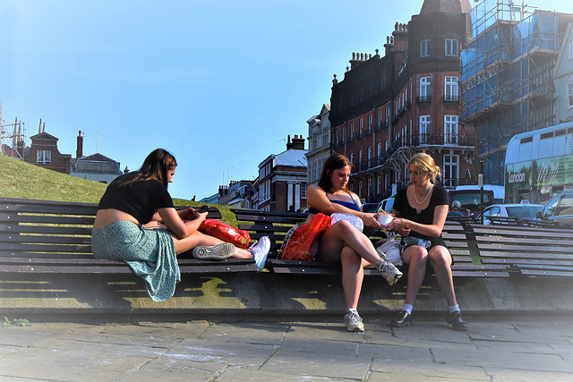 Two young ladies sharing ice cream, and one stroking her phone!