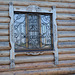 Окно с решеткой и наличником в деревянном здании