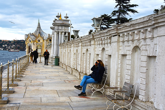 Lady sitting on bench taking pictures.