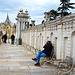 Lady sitting on bench taking pictures.