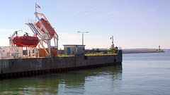 Rettungsboote und Hafenmole mit Leuchtturm