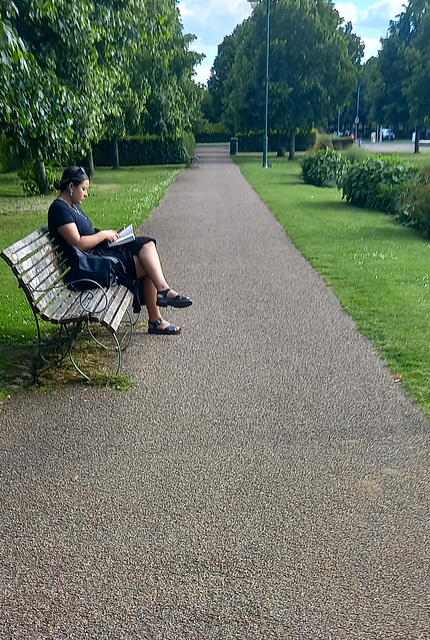Lady sitting on a bench in the park Lady sitting on a bench in the park