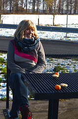 Füsun sitting on bench looking at tangerine and mince pie.