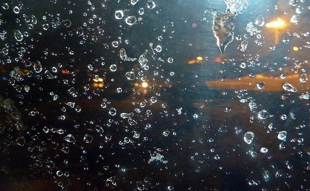 Eis und Wasserperlen am Flugzeugfenster nach dem Start