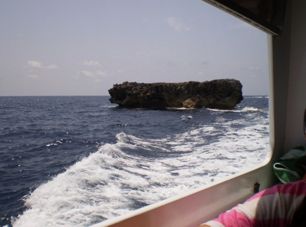 Between the coastline and a rock.