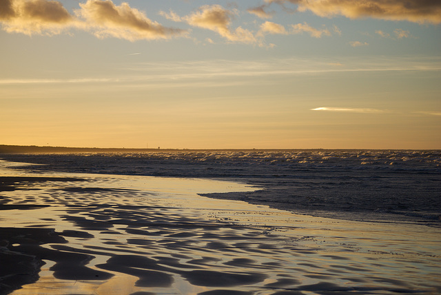 Der nasse Sand und die Wellen beim Sonnenuntergang