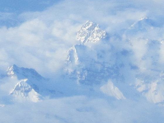 Snow capped mountains peeking out of the clouds