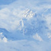 Snow capped mountains peeking out of the clouds