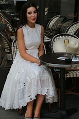 Dans un beau quartier de la capitale , jeune femme à la coupe de champagne et claquettes Christian Dior à 623 euros .