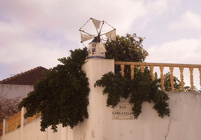 Miniature windmill on top of wall's corner.