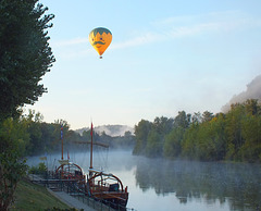 Gabarres à La Roque Gageac survolées par une montgolfière au petit matin.