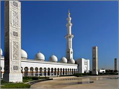 AbuDhabi : esterno del grande cortile al sole del mattino - un minareto ad angolo e tre obelischi delimitano l'area sul lato di levante