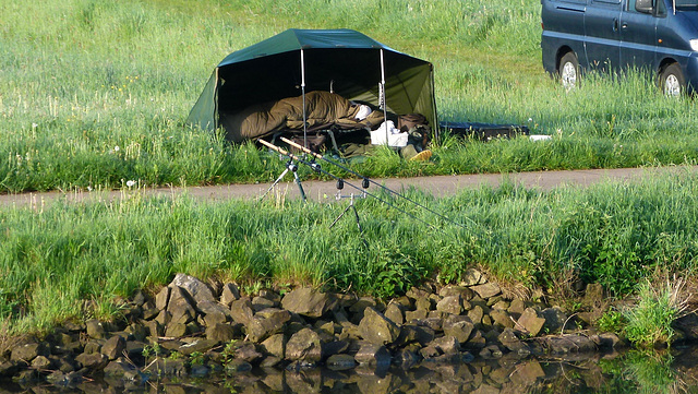 Der frühe Angler hängt den Wurm.