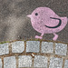 Poussin rose tournant en rond sur un trottoir parisien