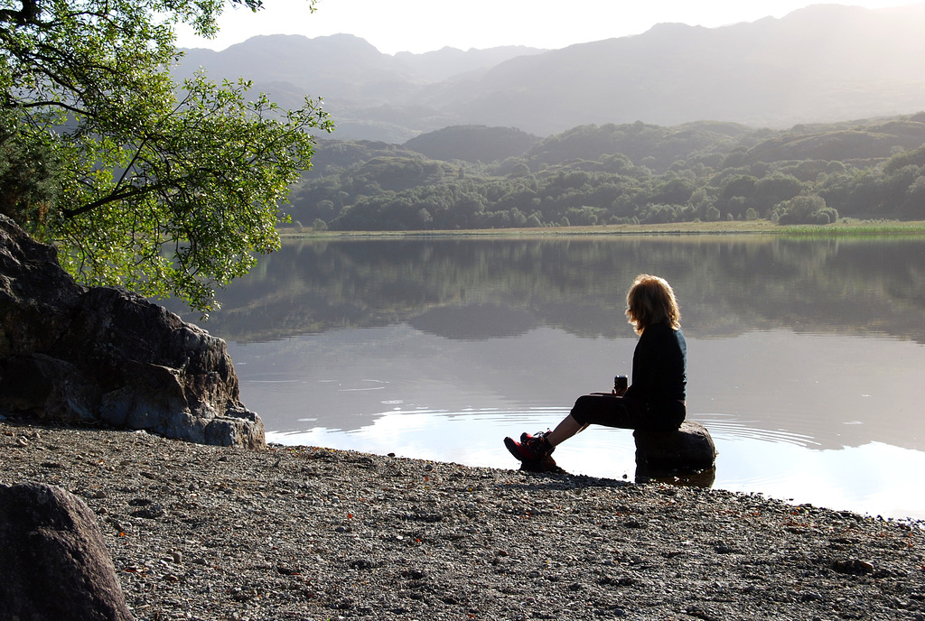 Füsun sits by the lake wearing red boots