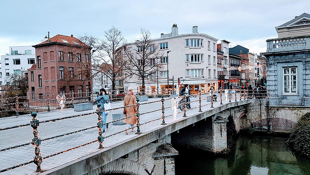 Visitors to Mechelen city walk over the lively Dijle