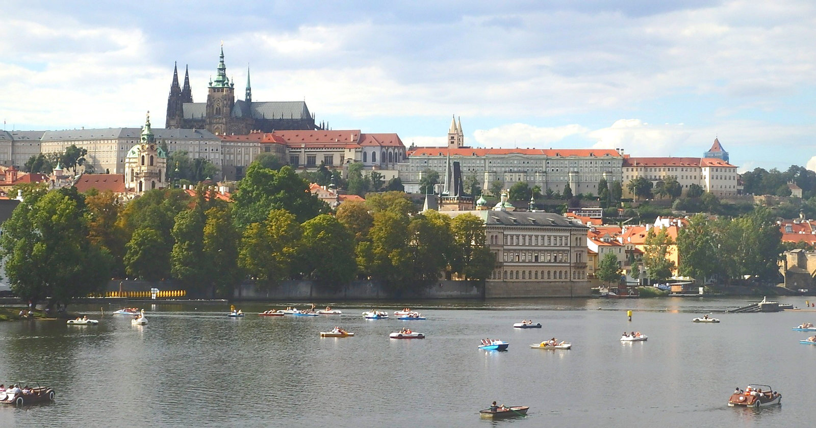 Praga Kastelo kaj la rivero Moldavo kun boatemuloj