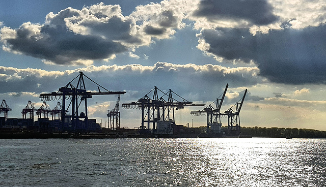 Wolkenbestückte Krananlagensilhouette.