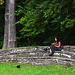 Lady sitting on stone bench reading a book.