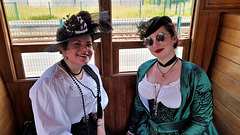 Two ladies sitting on wooden train bench