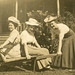 Three Women with Hats and a Wheelbarrow
