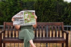 Sitting on bench reading newspaper!