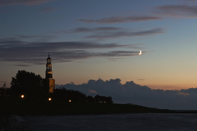 Kirchturm und Mond am Ijsselmeer im abendlichen Zwiegespräch