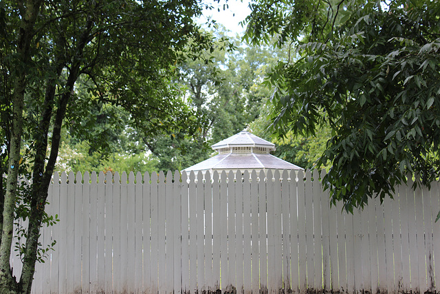 HFF EVERYONE...A fence partially hiding a large nice Gazebo in their backyard.