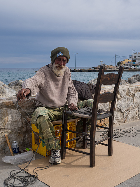 Ein alter Mann repariert einen Stuhl