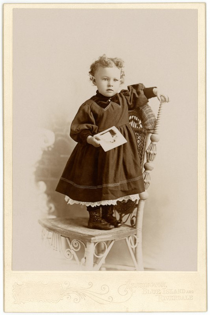 Girl Holding Photo and Standing on Chair