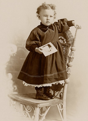 Girl Holding Photo and Standing on Chair (Cropped)