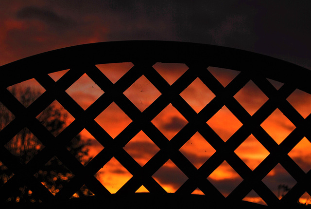 Sunset viewed through a fence.