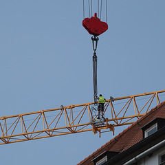 Über die Häuser und die belebte Straße gehoben und am Kranturm befestigt.