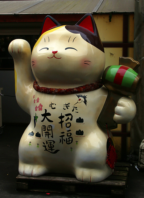 Maneki-neko , le chat porte-bonheur . La patte droite levée est relative à l'argent et à la chance , la gauche levée favorise l'amitié ...